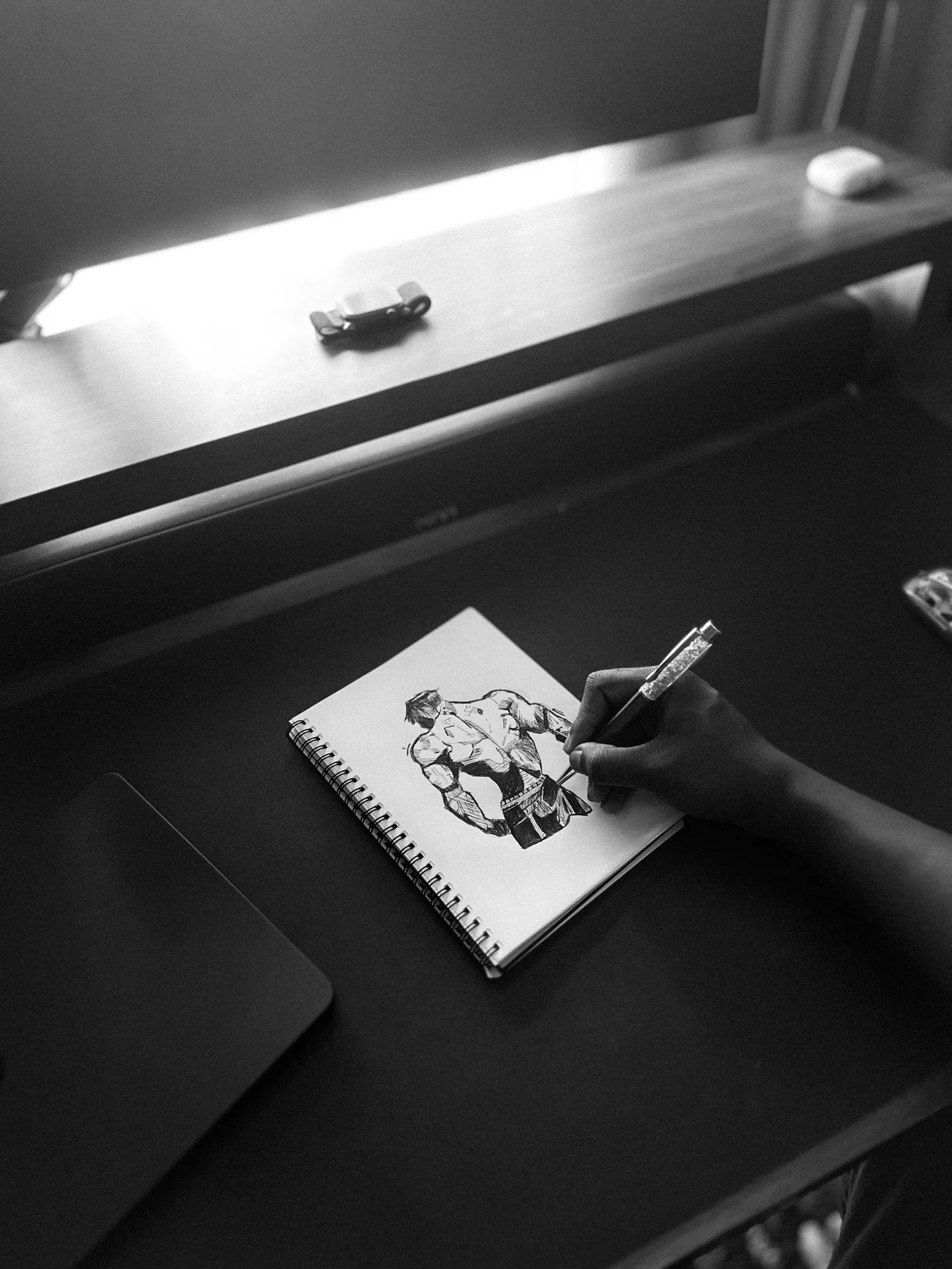 Artist drawing in a sketchbook at a desk
