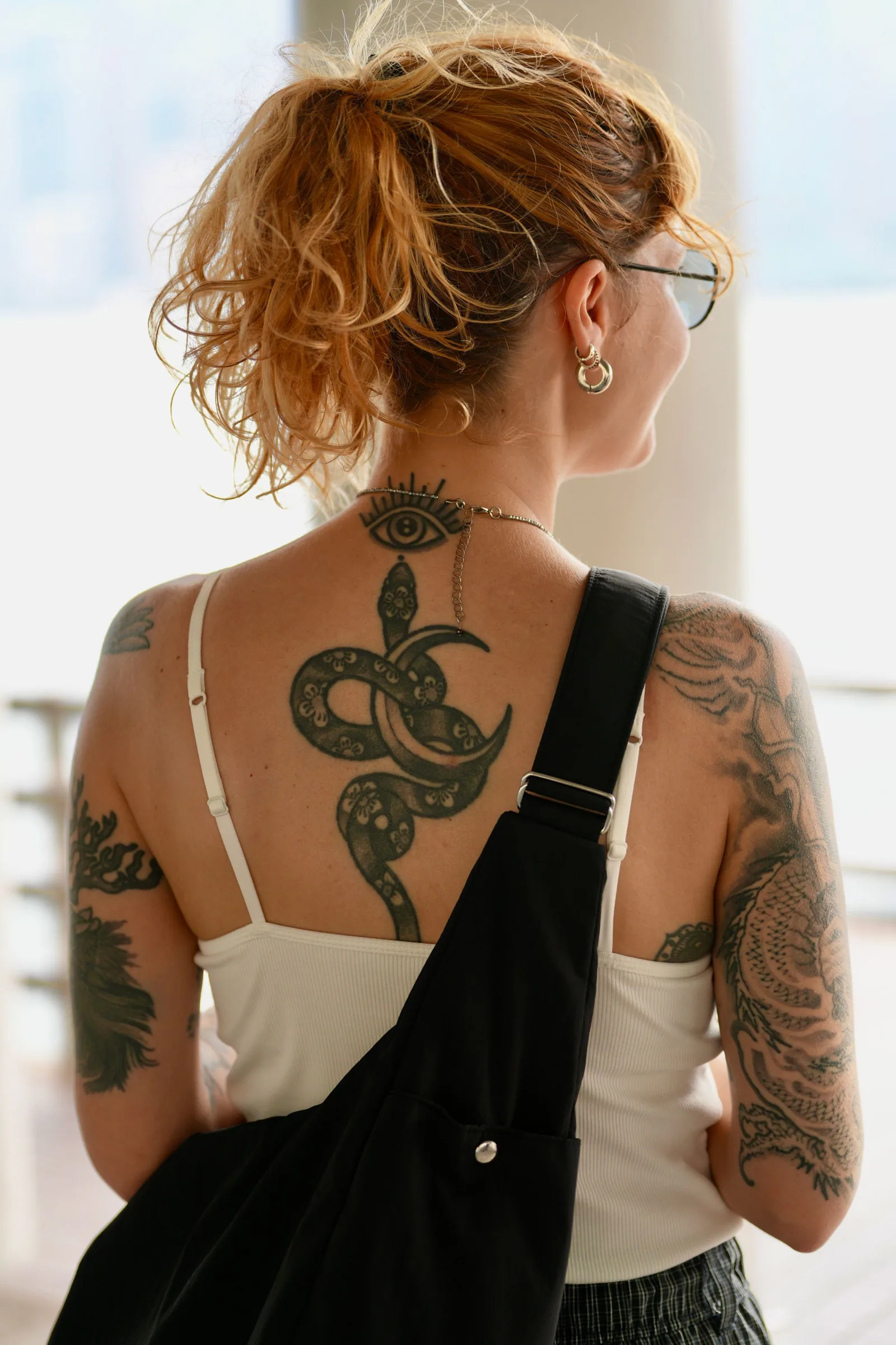 Snake and crescent moon tattooed down the spine, with sleeves on both arms