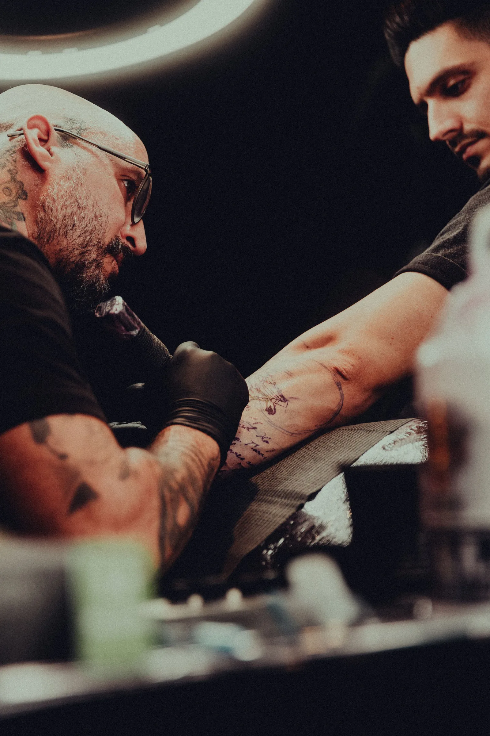 An artist tattooing a client's arm