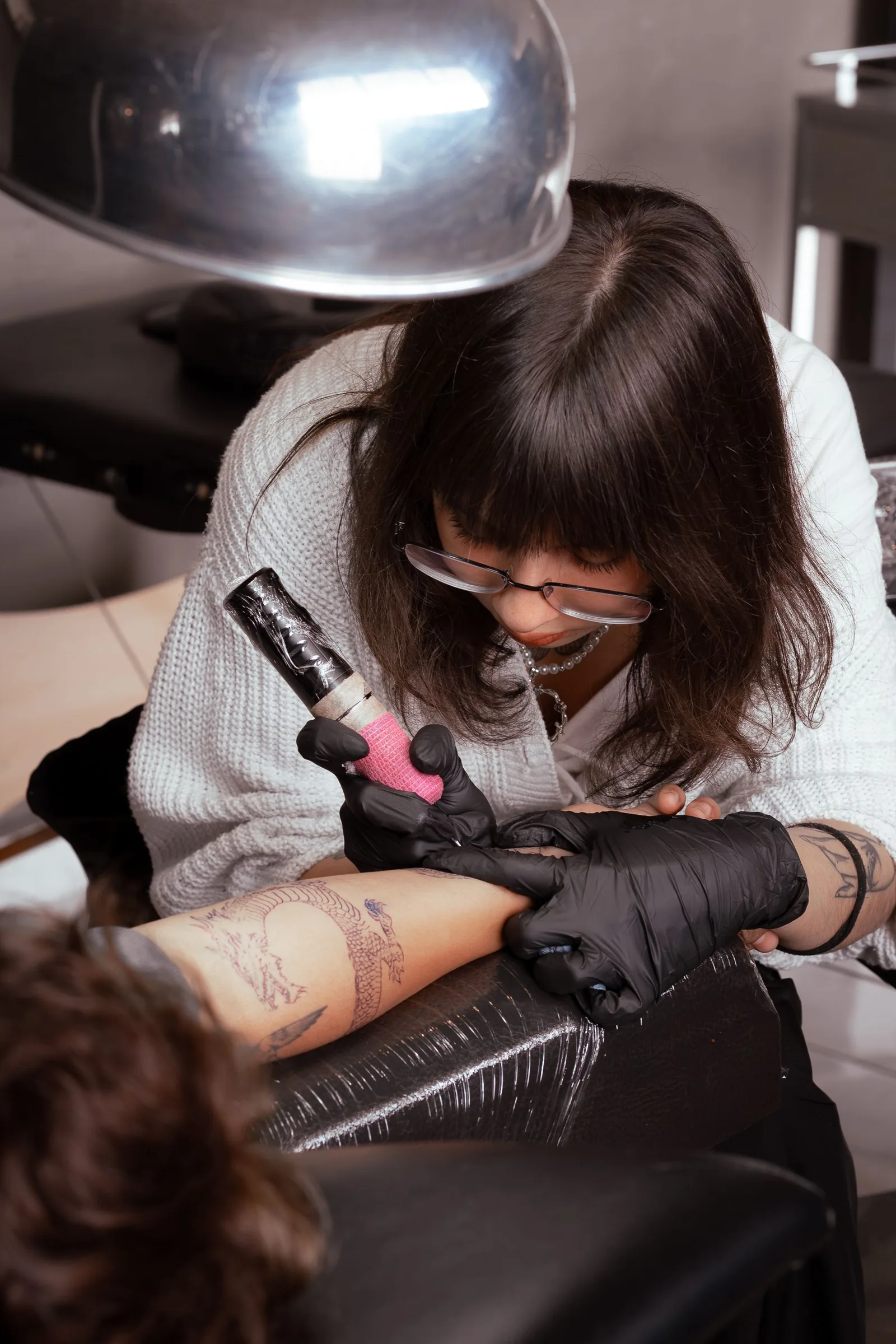 Gloved hands holding a tattoo machine