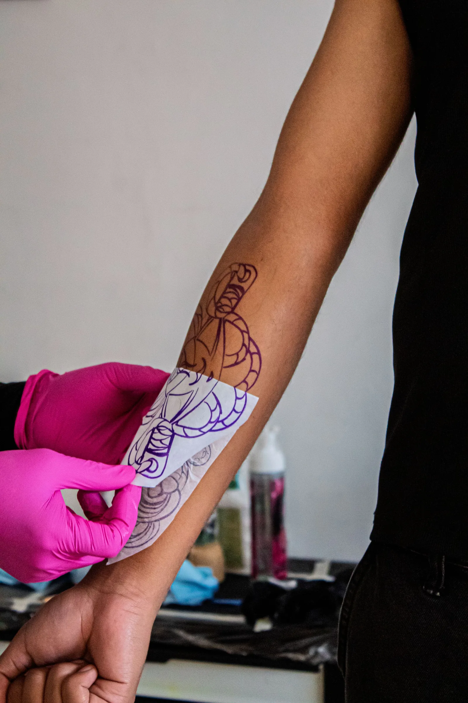 A stencil being placed on a forearm before tattooing