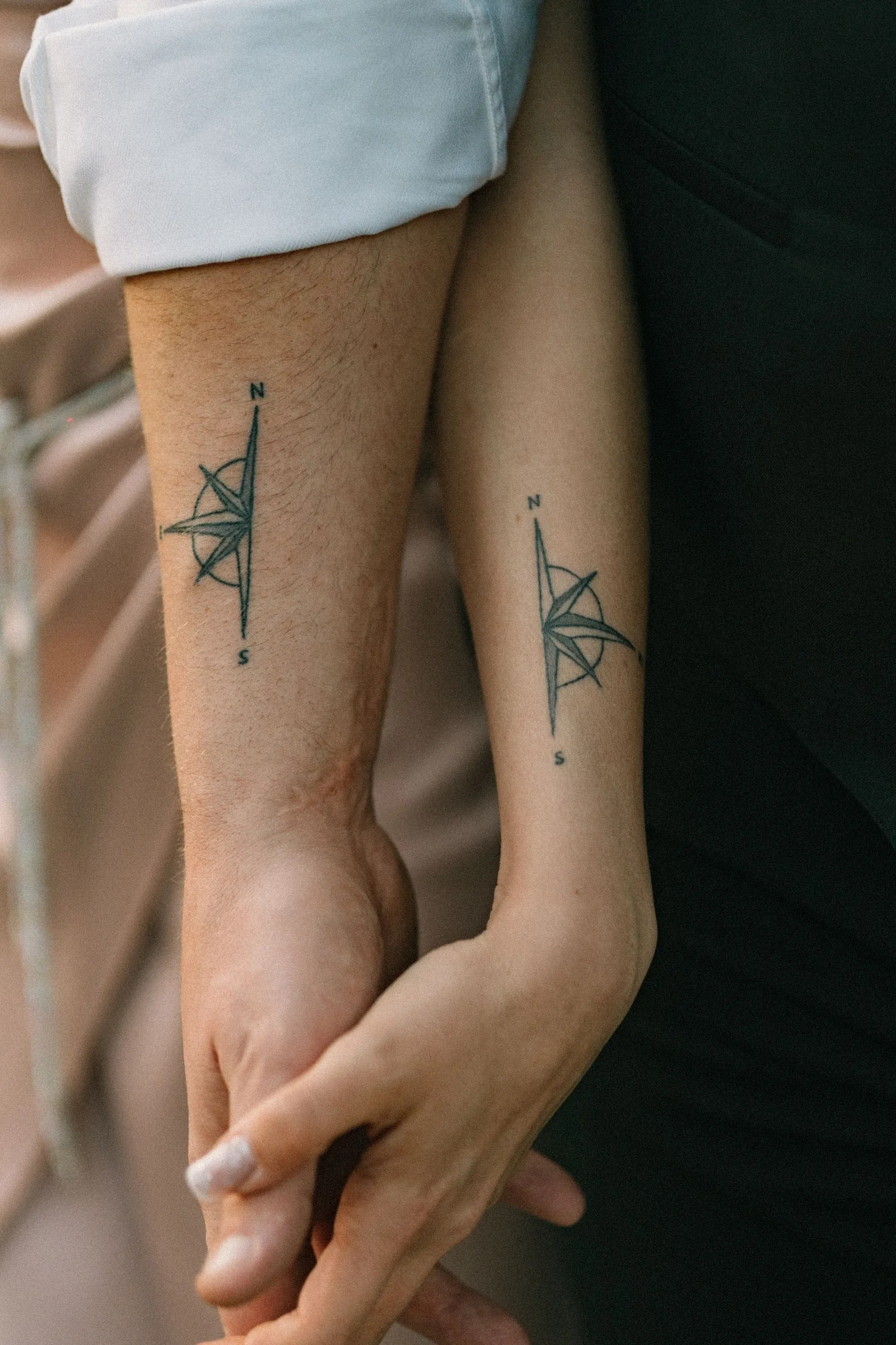 Matching compass tattoos on two forearms