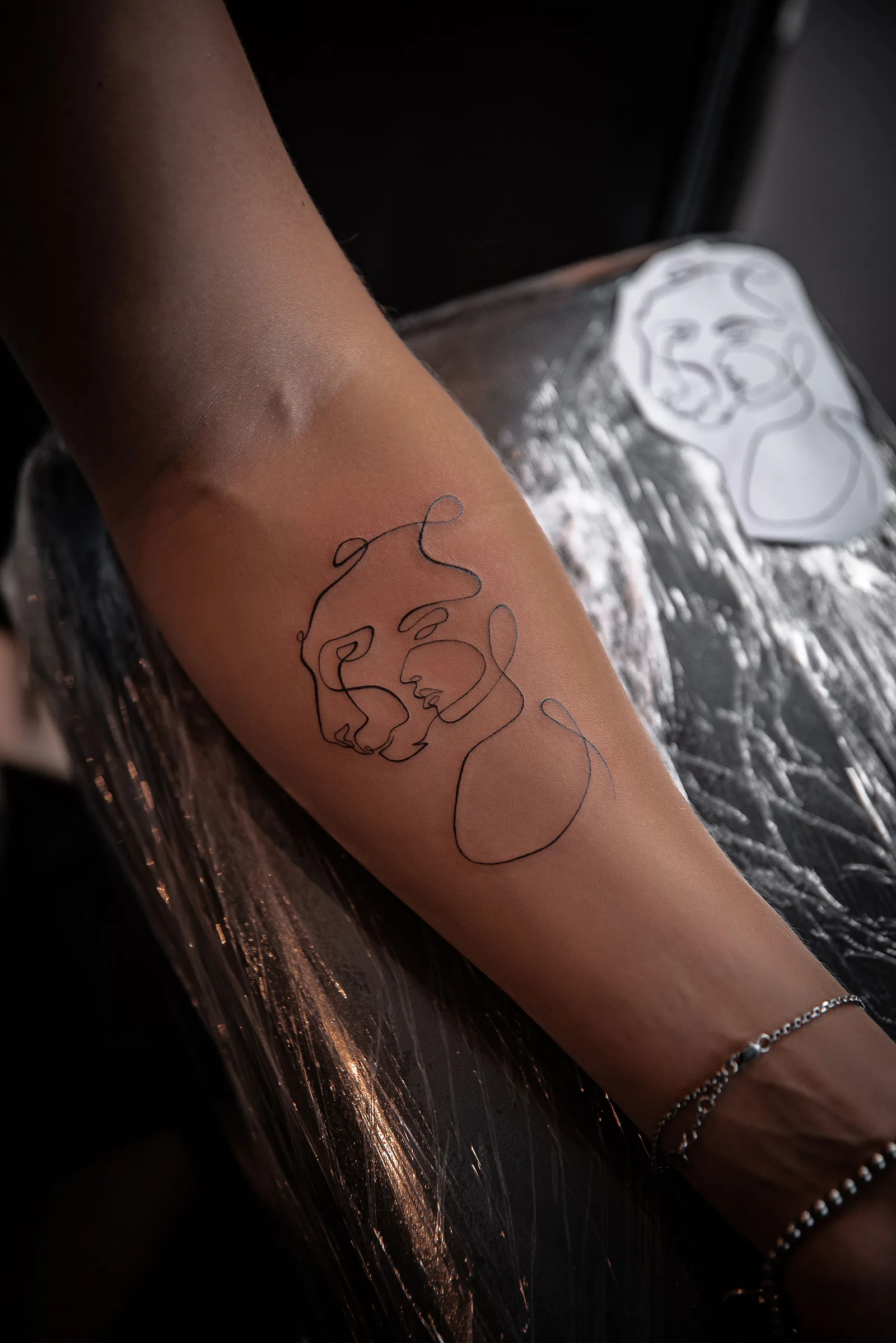 One line face tattoo on a forearm